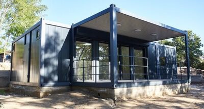 Imagine care ilustrează un proiect de construcții modulare, cu containere transformate în case moderne, ce evidențiază designul inovativ și eficiența spațială.