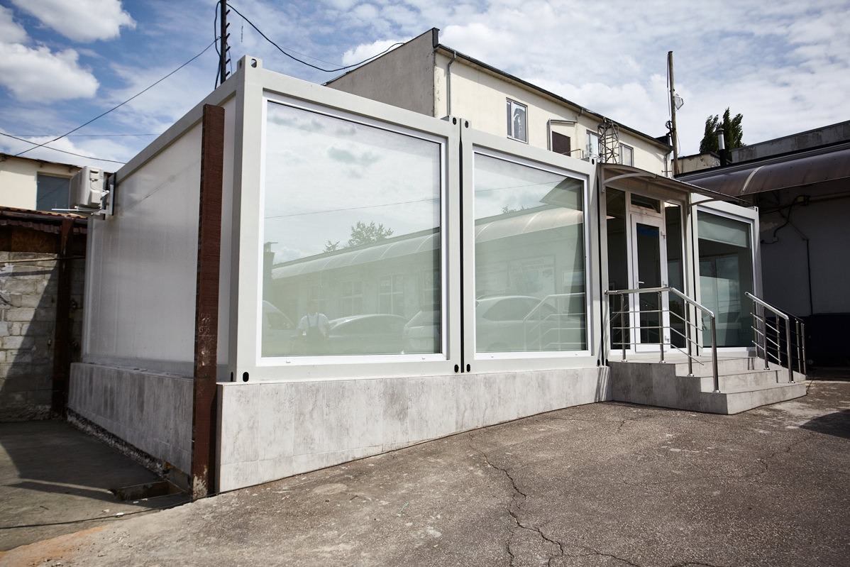O imagine cu containere modulare moderne, utilizate în construcții, arătând cum pot fi transformate în case funcționale și elegante, integrate armonios în peisajul urban.