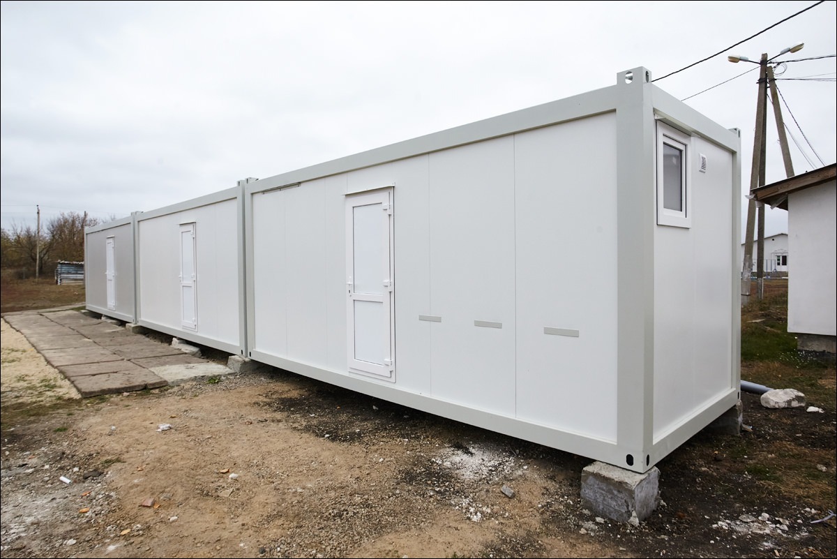 Imagini cu construcții modulare din containere, prezentând case moderne și funcționale, integrate armonios în peisaj.