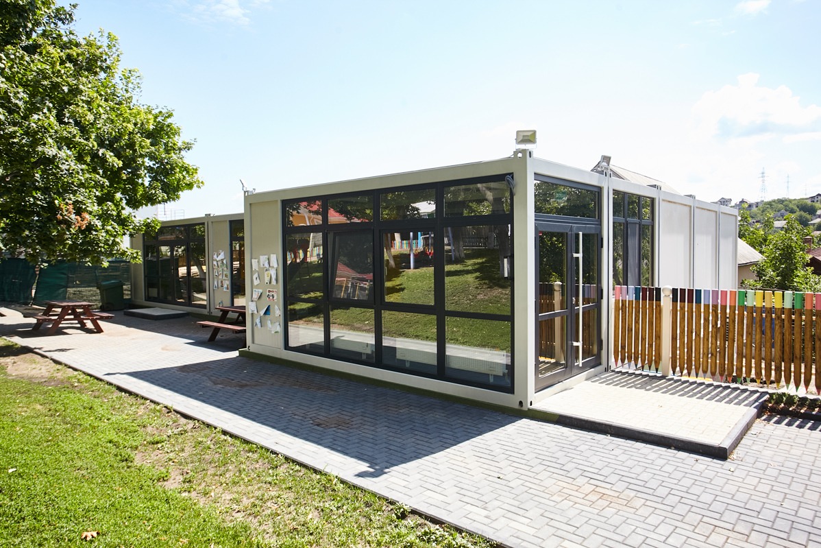 Imagine care prezintă un proiect de construcție modulară, având ca element principal un container transformat în casă, evidențiind soluțiile inovative pentru construcții eficiente.