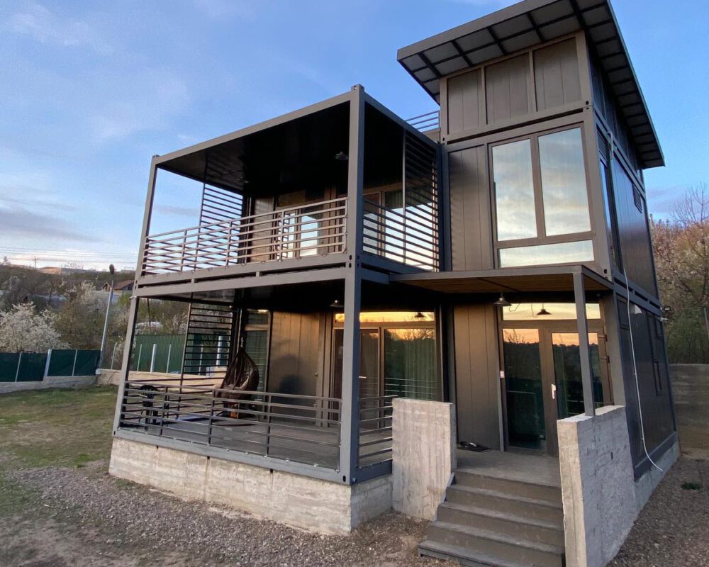 Imagine cu containere modulare utilizate pentru construcții, prezentând o casă modernă, confortabilă, construită din module prefabricate.