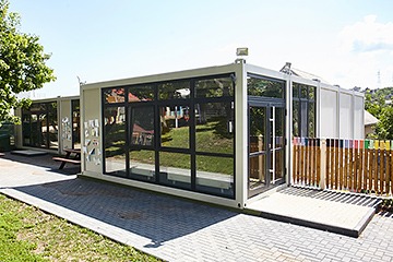 Imagine cu un complex de construcții modulare realizate din containere, evidențiind case moderne și funcționale, amplasate într-un peisaj urban.