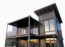 Imagine care ilustrează construcții modulare din containere, prezentând o casă modernă și funcțională, evidențiind designul eficient și utilizarea optimă a spațiului.