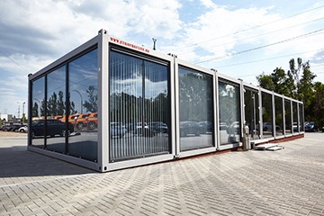 Casă modulară din containere, construită cu un design modern, situată într-un peisaj natural, evidențiind inovația în construcții.