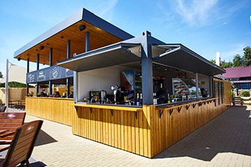 Casa modulară construită din containere, prezentând un design modern și funcțional, înconjurată de natură.