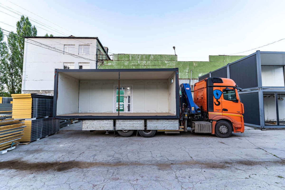 Imagine cu construcții modulare realizate din containere, evidențiind procesul de fabricație și designul inovator al caselor.